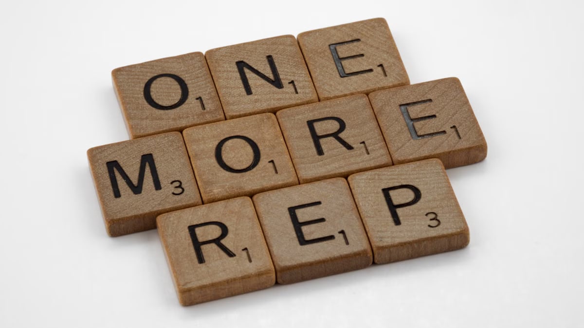 Scrabble tiles arranged to spell 'One More Rep', symbolizing fitness motivation.